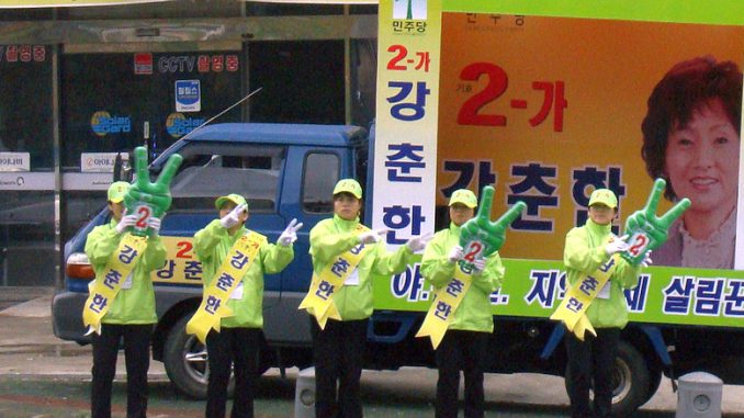 Wahlkampf in Süd-Korea, 5 Wahlhelfer vor einem Werbeplakat auf einem Kleinlaster