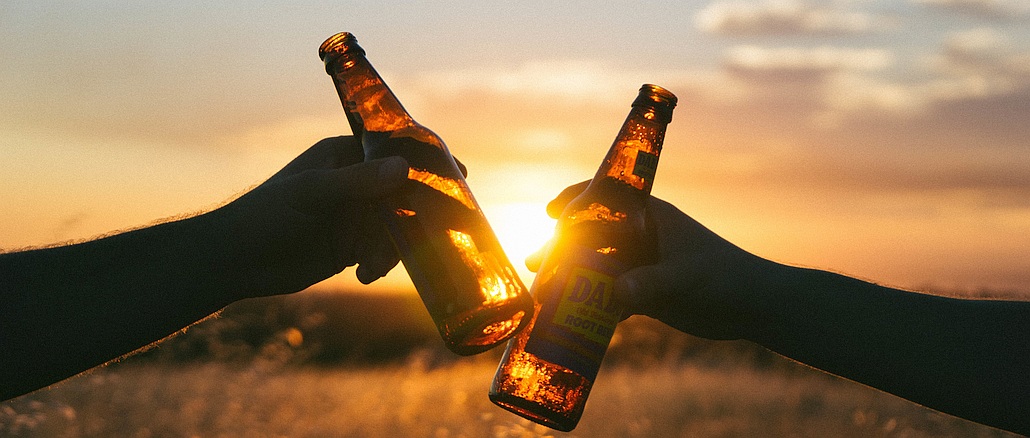 Feierabend: Anstoßen mit zwei Bierflaschen in der Abendsonne