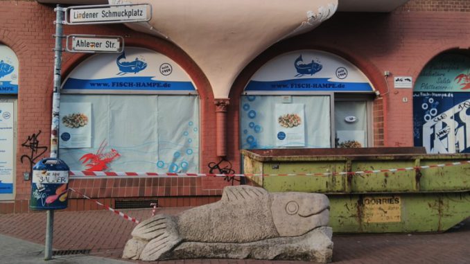 Steinskulptur Fisch vor vor geschlossenem Fisch-Hampe am Schmuckplatz