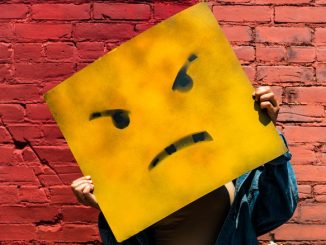 Wütend! Gelbes Quadrat mit zornigem Gesicht vor roter Ziegelwand