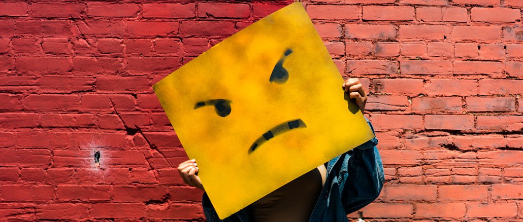 Wütend! Gelbes Quadrat mit zornigem Gesicht vor roter Ziegelwand